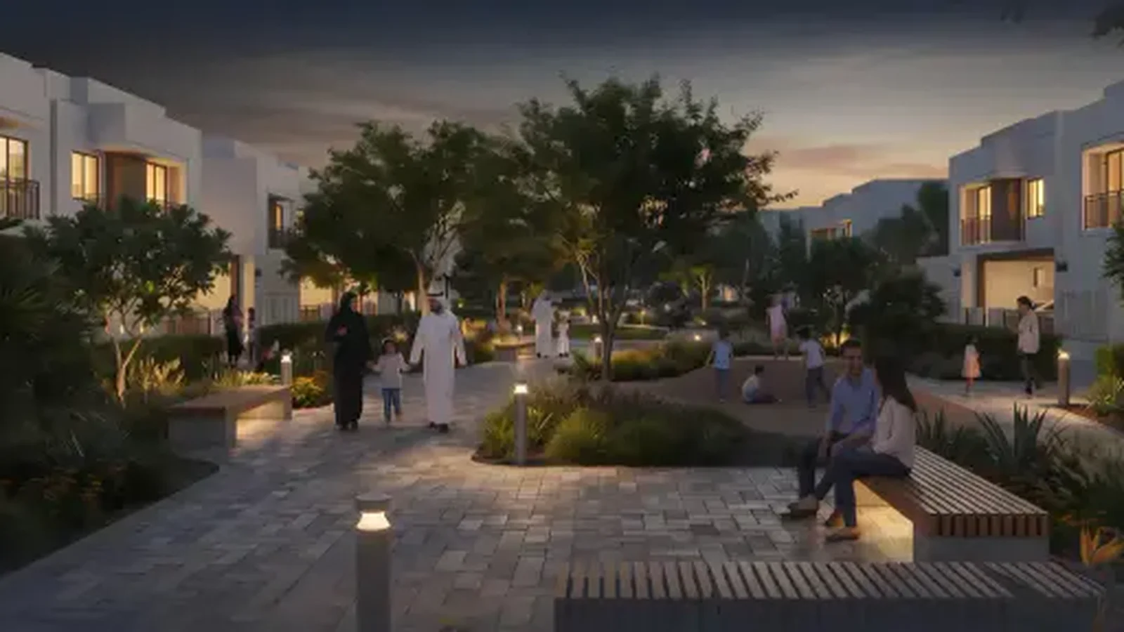 Lit pedestrian walkway through Al Ghadeer landscaping after dark