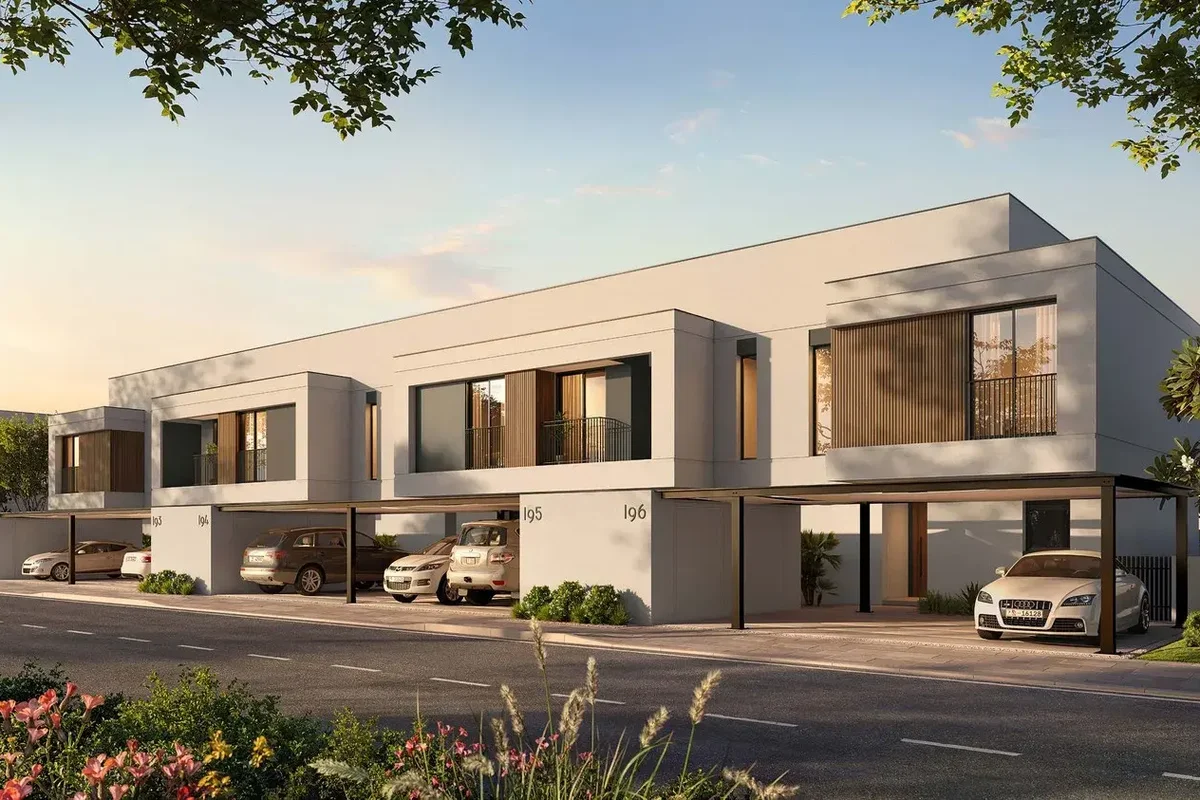 Daytime street of Al Ghadeer Gardens townhouses with parked cars and trees